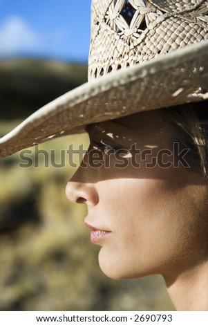 Close-up profile of mid-adult Caucasian woman wearing straw cowboy hat.