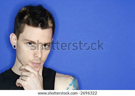 Young adult Caucasian male pierced ear and tattoo.