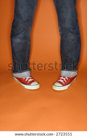 Person in jeans and sneakers with feet turned inward.