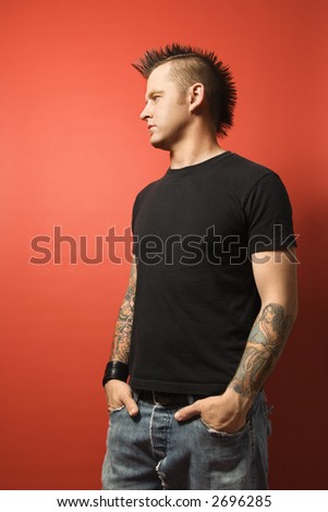 stock photo Caucasian man with mohawk and tattoos standing with hands in 