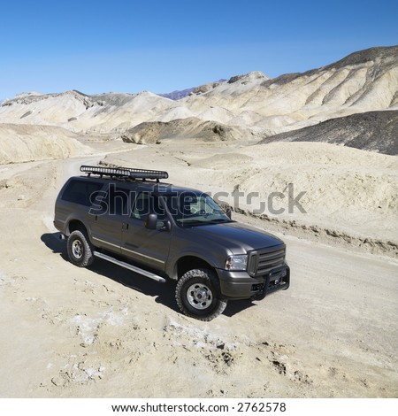Four wheel drive truck on dirt road in barren landscape in Death Valley National Park.