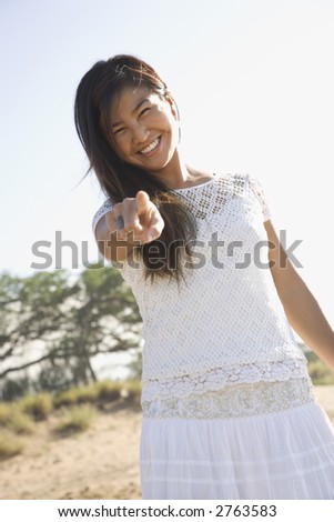 Young adult Asian female pointing at viewer.