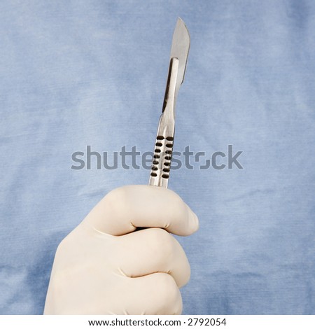 Close-up of male surgeon\'s gloved hand holding scalpel.