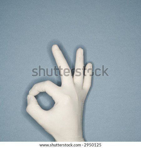 Hand wearing white rubber glove making a gesture meaning okay.