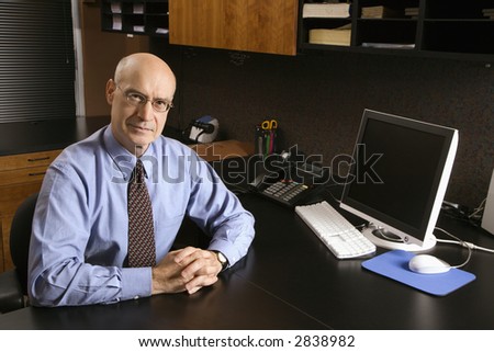 Caucasian middle-aged businessman sitting at desk in office.