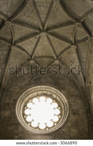 Rib-vaulted ceiling and sunlit window in Jeronimos Monastery in Lisbon, Portugal.