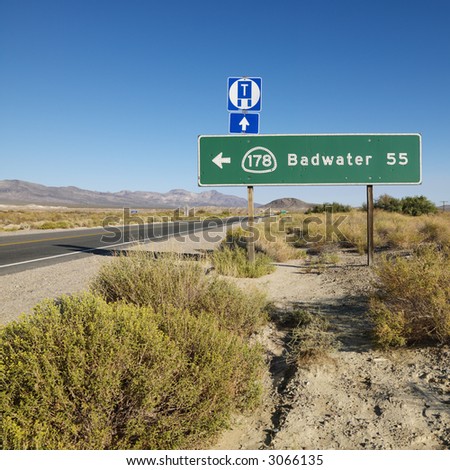Road sign on side of desert road with direction to Badwater, Death Valley.