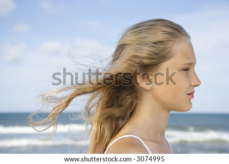stock photo Caucasian preteen girl on beach with hair blowing in wind