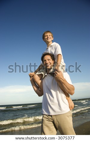 stock photo Caucasian father with preteen boy on shoulders on beach