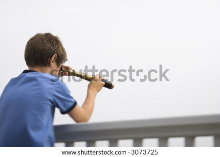 Caucasian pre-teen boy leaning on railing looking through telescope.