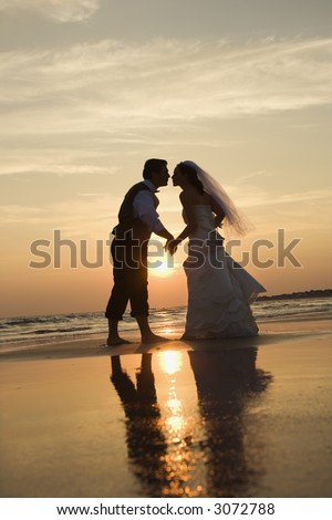 Holding Hands Kissing. adult male groom and female bride holding hands and kissing barefoot