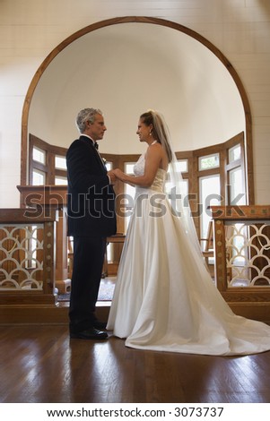 Protrait of bride and groom holding hands at the alter of a church.