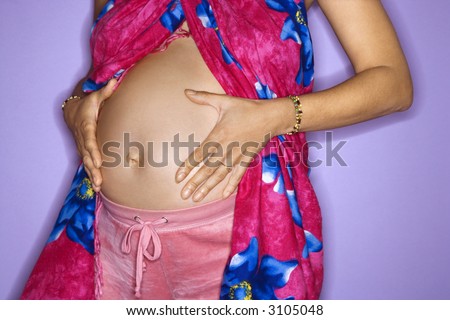 Close up portrait of expecting female with hands on stomach.