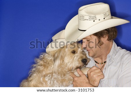 Fluffy brown dog and male Caucasian young adult wearing cowboy hats.