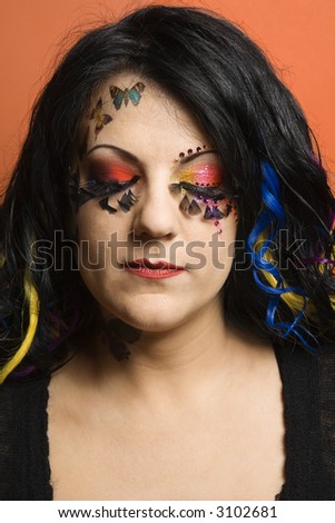 Portrait of Caucasian woman in unique makeup and hair with eyes closed.