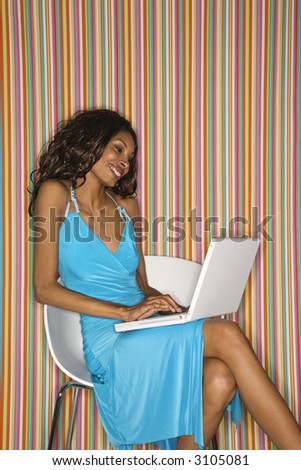 Young adult African American female face sitting with laptop.