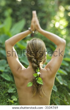Rear view of nude Caucasian mid-adult woman with hands overhead in yoga pose.