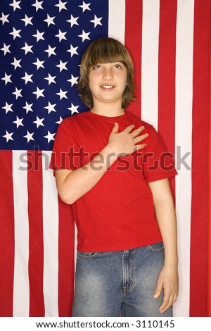 Portrait of Caucasian boy with hand over heart with american flag background.