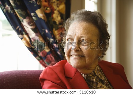 Elderly Caucasian  woman by window at retirement community center.