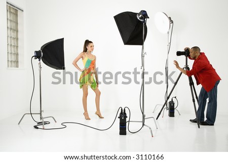 Young adult female Caucasian model being photographed in studio by young adult African American male photographer.