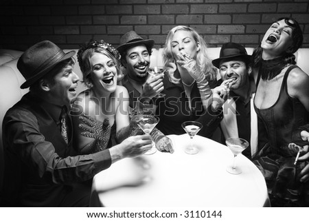 Group of Caucasian prime adult retro males and females sitting at table in lounge laughing.