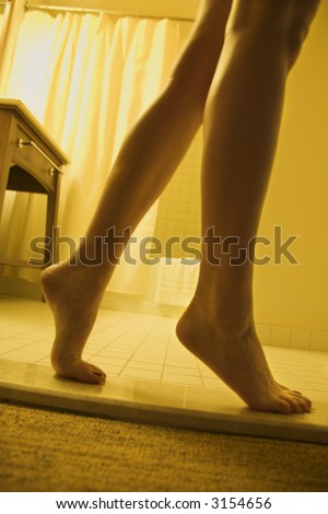 Bare legs and feet of woman standing on tiptoe.
