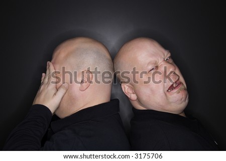 Caucasian bald mid adult identical twin  men standing back to back with sad expressions.