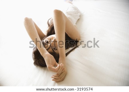 Pretty young Caucasian woman lying on bed wearing nightgown.