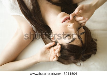 Pretty young Caucasian woman lying on bed wearing nightgown.