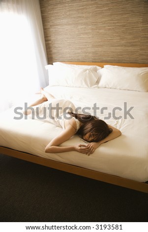 Portrait of pretty Caucasian young woman wearing nightgown lying on bed.