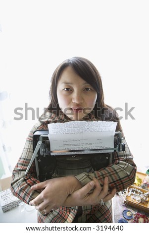 Pretty young Asian woman holding typewriter.