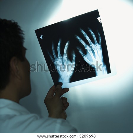 Asian American male doctor examining x-rays.