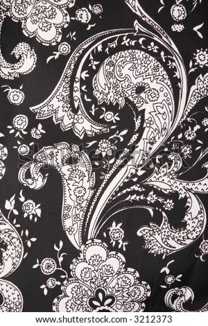 Close-up of black and white vintage fabric with flowers and paisley printed on polyester.