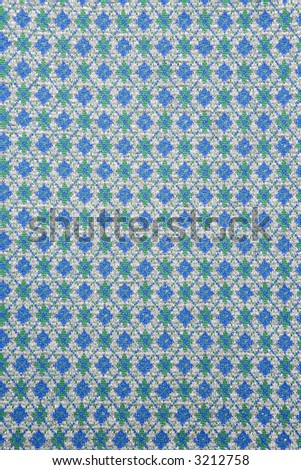 Close-up of woven vintage fabric with repetitive blue and green diamonds.