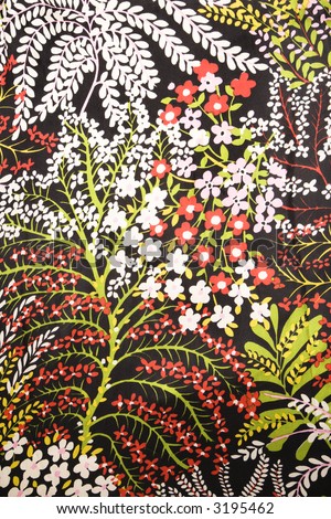 Close-up of vintage fabric with red green and white flowers printed on polyester.