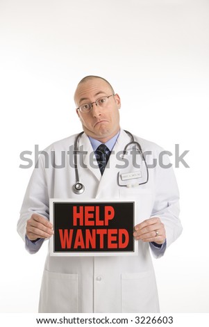 Caucasian mid adult male physician holding help wanted sign.
