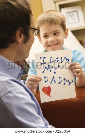 Caucasian boy giving mid adult father a drawing.