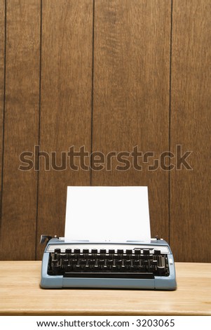 Vintage blue typewriter on desk with wood paneling.
