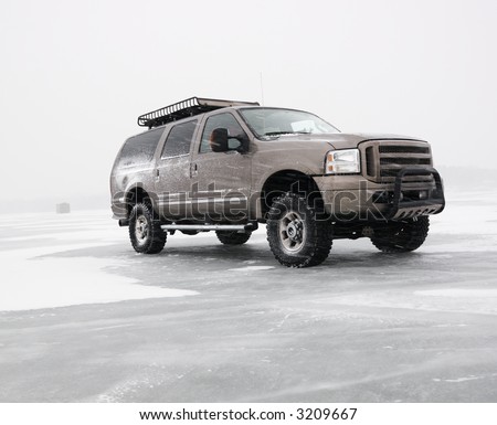 Four wheel drive truck with all terrain tires and roof rack parked on desolate frozen lake in Green Lake, Minnesota, USA.