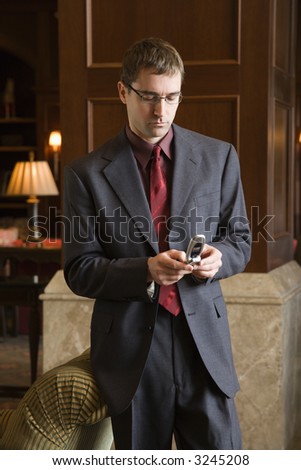 Caucasian mid adult businessman looking down at cell phone.