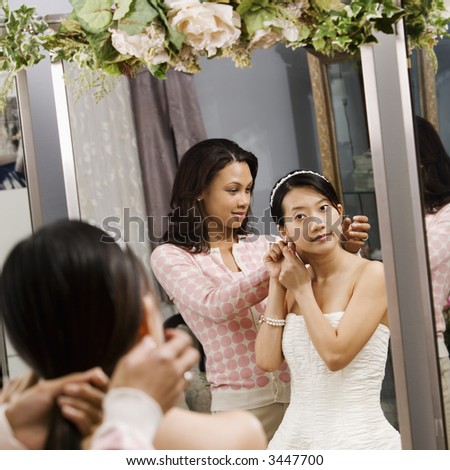 African-American woman helping Asian bride with hair.