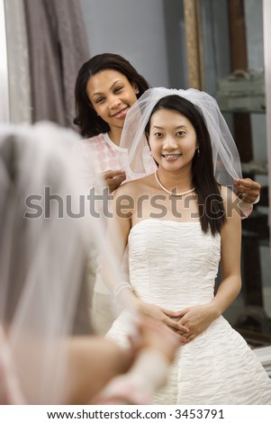 African-American friend holding Asian bride\'s veil.