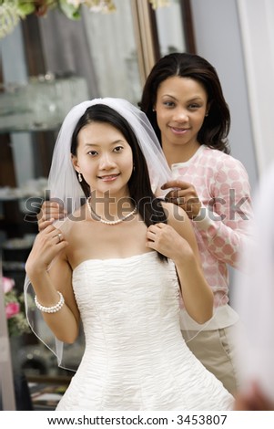 African-American friend holding Asian bride\'s veil.