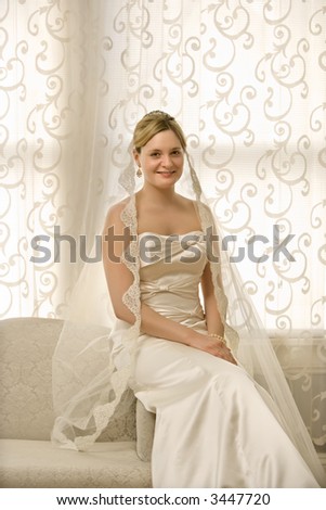 Portrait of Caucasian bride sitting on love seat.