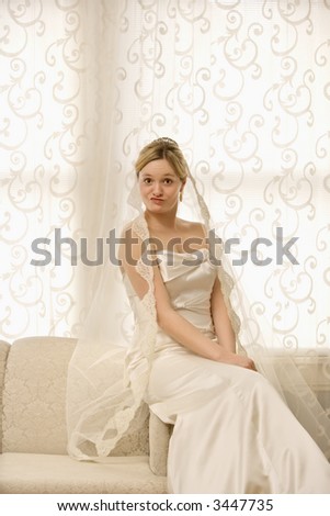 Portrait of Caucasian bride sitting on love seat making a funny expression.
