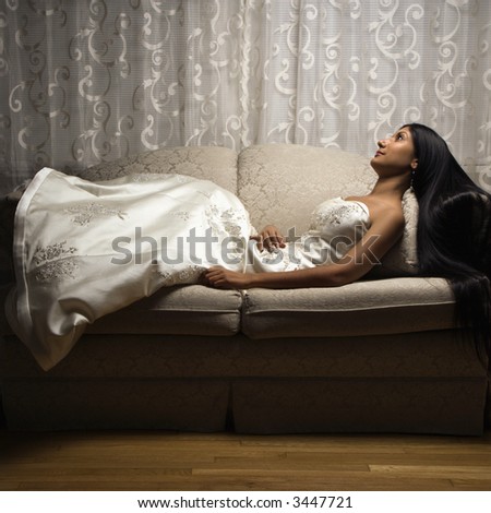Portrait of an Indian bride lying on love seat.