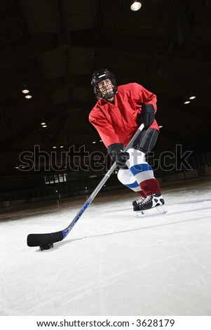 Woman hockey player skating on ice lining up to shoot puck.