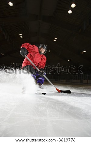 Caucasian woman hockey player sliding kicking up ice.