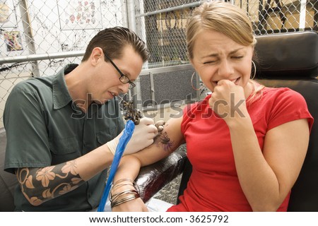 stock photo Caucasian male tattoo artist tattooing Caucasian woman