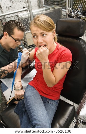 stock photo Caucasian male tattoo artist tattooing Caucasian woman